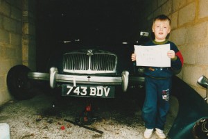 Photograph of a young boy holding the proof of date for blue MGA Roadster