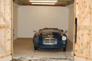 Photograph of a blue MGA Roadster in a new clean shed