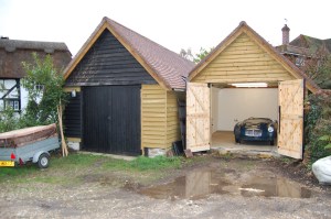 Photograph of two newly built shed one of which has a blue MGA Roadster