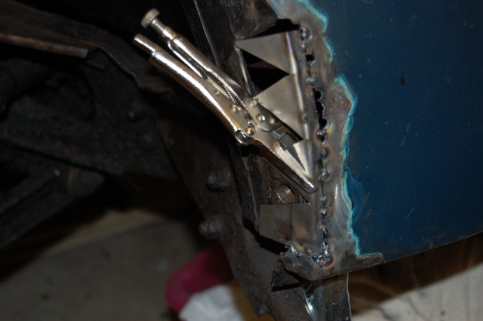 Not being an expert, the curved shape of the shroud caused me anxiety and the repair solution will not be that taken by a professional. I fabricated a backing fillet with a flange and cut-outs enabling a curve and tack welded this to the shroud face and flange, to give a solid backing for lead loading. The captive nut was welded in place ensuring it was in exactly the right position to match up to the locating hole in the wing flange. The wing was trial fitted at this stage to ensure fit.