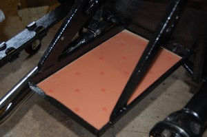 Single 12 volt battery conversion. On a right hand drive car it makes sense to position the single battery on the passenger side, from a weight distribution point of view. On the original cradle there is a raised centre bar across the middle, designed to contain the smaller 6 volt battery, which is located in the outer (rearward) half of the carrier.To accommodate the larger 12 volt, this centre bar needs to be flattened. I then made a thin floor out of brass covered circuit board and bonded it to the frame, then sealed it with mastic.