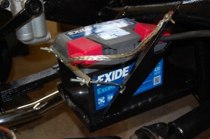 Battery retaining clamp fabricated from scrap, with hooks mounted in original locating holes.